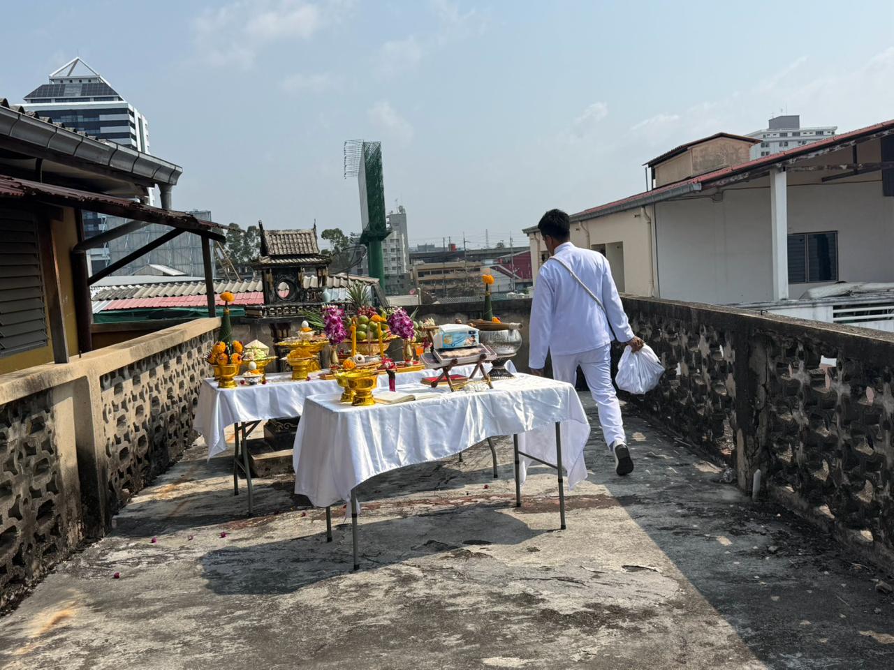 Rooftop ceremonial path with offerings and a man in white walking away after the rite