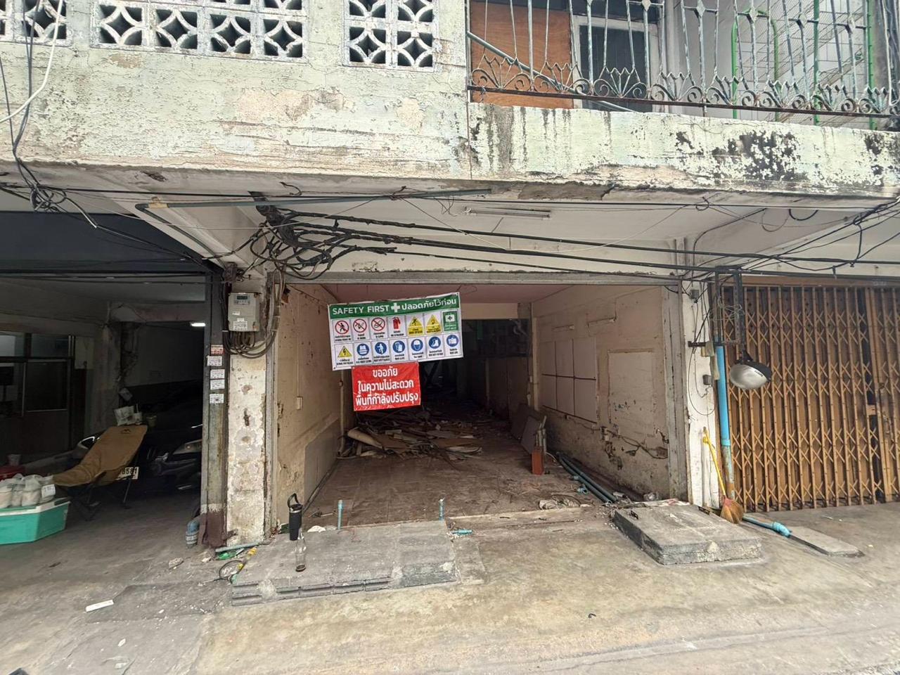 Open ground-floor bays at the building with safety signage and exposed renovation conditions
