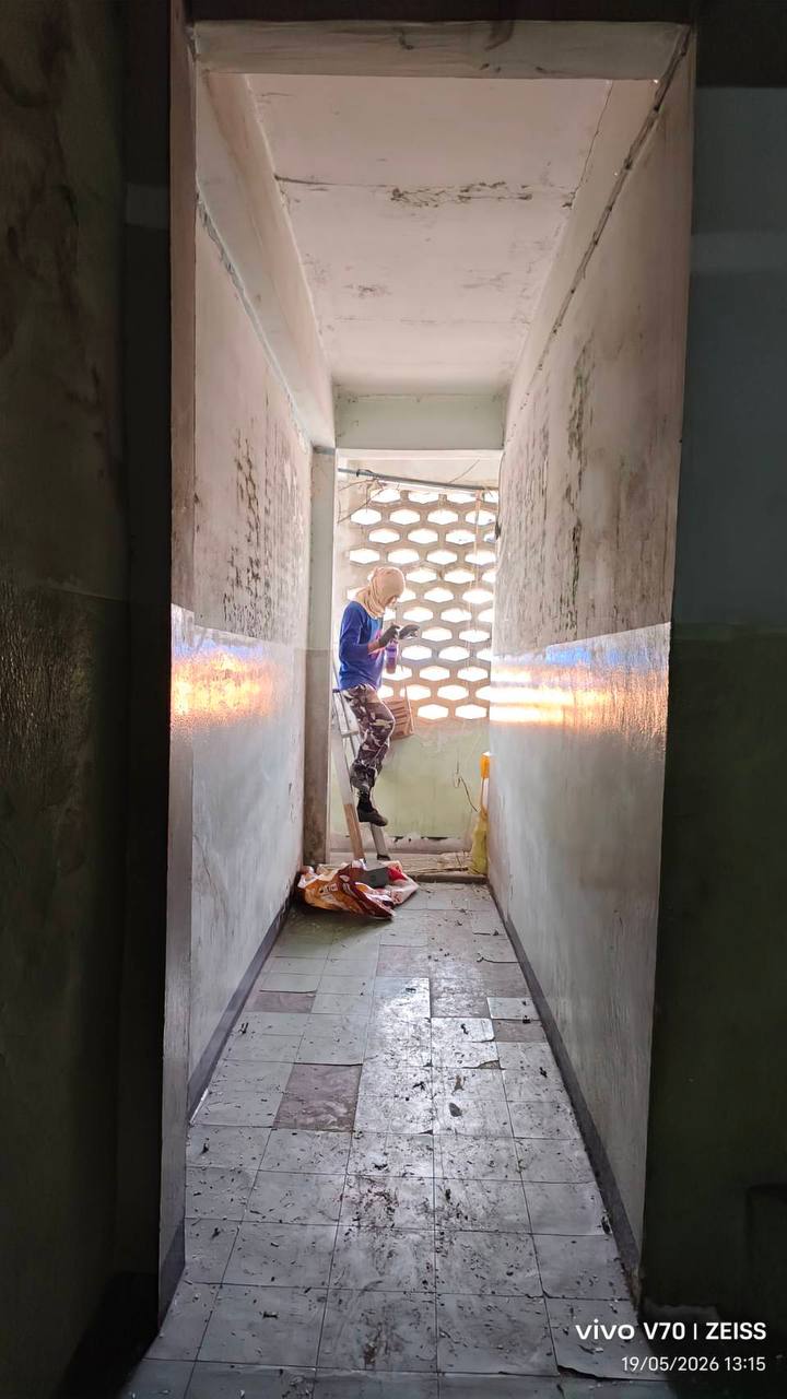 Narrow interior corridor at the rear building with a worker on a ladder during early stripping and clearing works