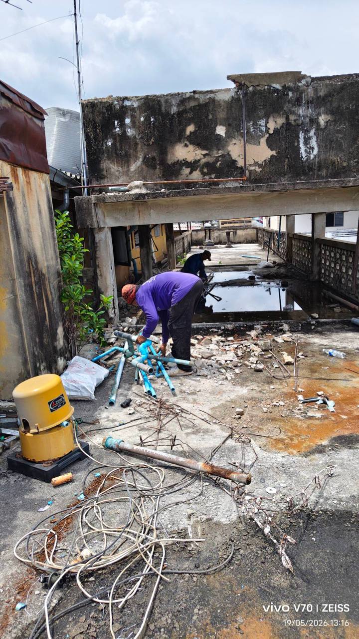 Workers clearing the rear exterior area at WITHIN with removed pipes, cables, and debris visible on the slab