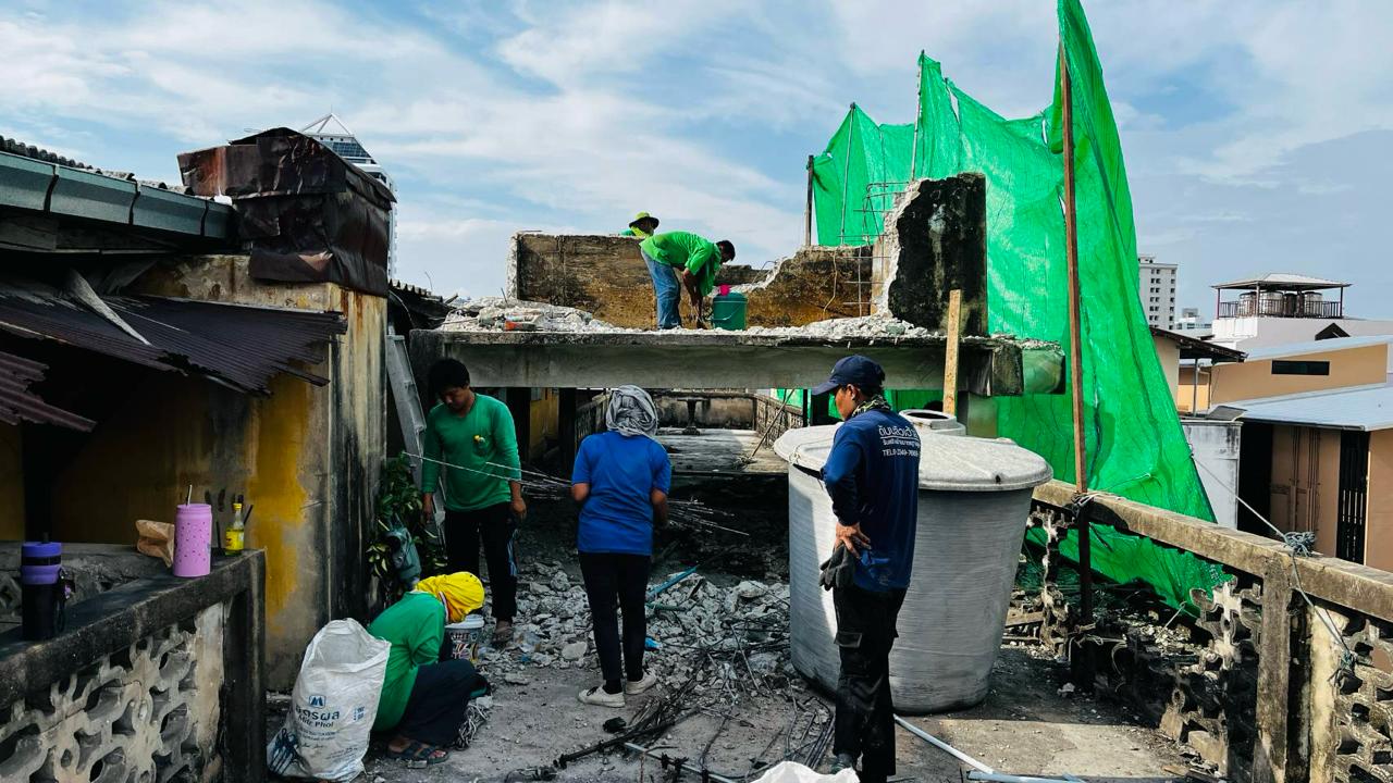 Workers on the top floor of WITHIN during the first day demolition began, with rubble, exposed rebar, and safety mesh visible