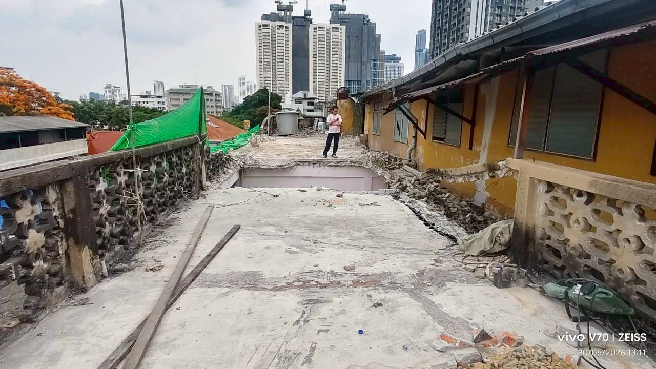 Wide view across the fifth floor at WITHIN showing a more open slab, rubble pushed to the edges, and a person standing at the far end for scale