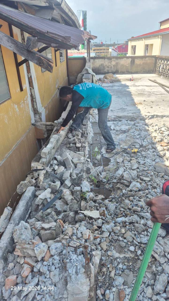 Worker on the fifth floor at WITHIN standing among broken concrete while clearing the edge of the demolition zone