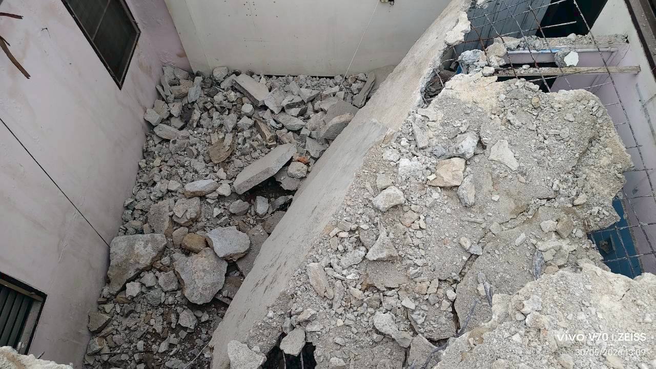 Close view down into the fifth-floor demolition opening at WITHIN with broken concrete and debris visible around the void