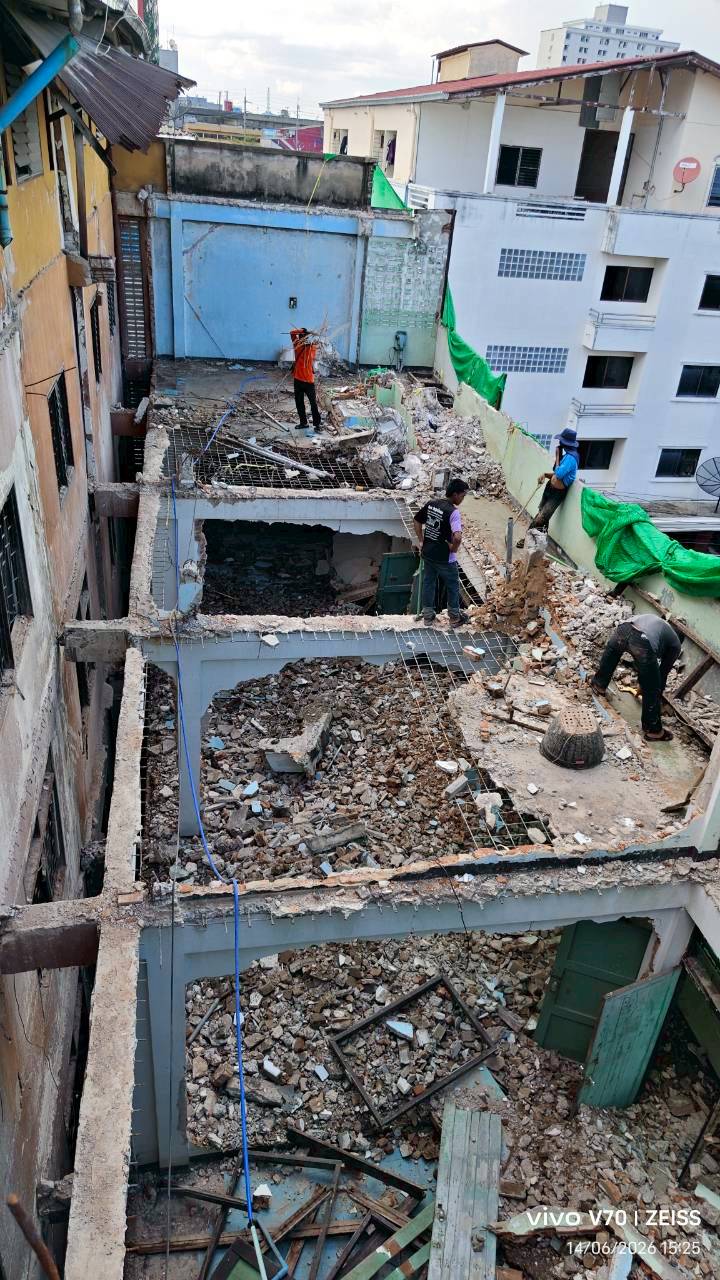 High view across the main building at WITHIN showing workers standing beside heavy rubble and multiple floor slabs cut open through the demolition zone
