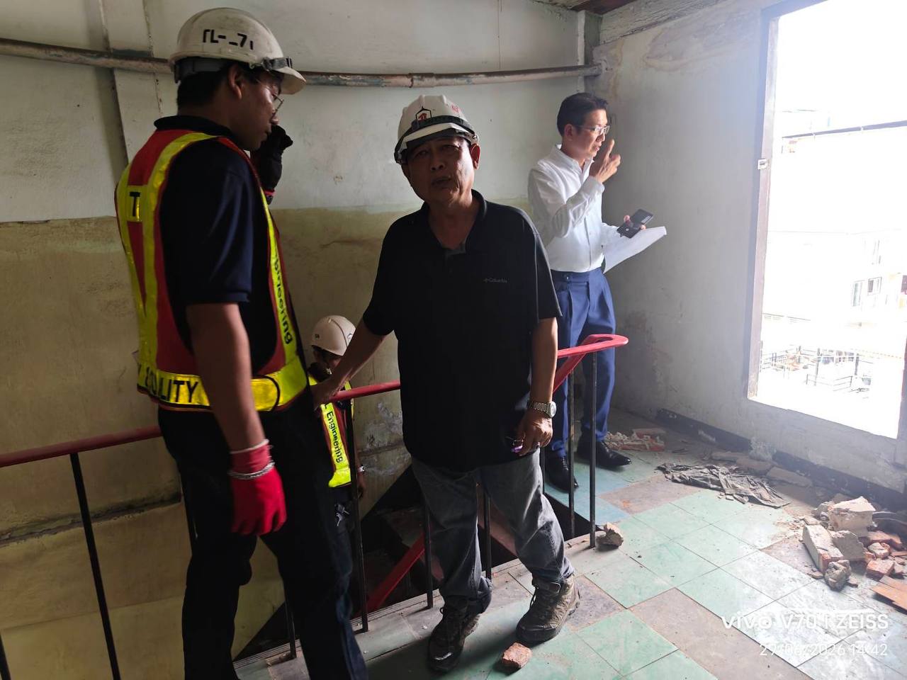 Thai Lift Company staff and site team gathered beside a stair opening inside the main building at WITHIN during an early inspection for future lift works