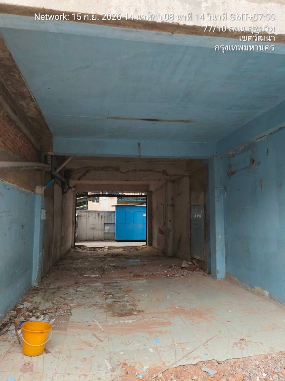 Long view through a stripped ground-floor shophouse at WITHIN with exposed walls, ceiling, and debris at the floor edges